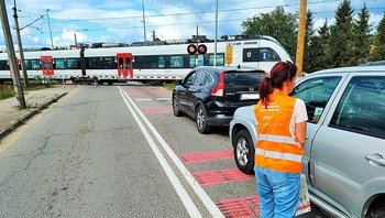 Koordynator kampanii podczas akcji ulotkowej, przejazd kolejowy, pociąg na torach