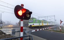 Pociąg na przejeździe, zamknięte rogatki, pulsujące światło