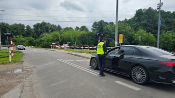 Sokista wręcza ulotkę kierowcy oczekującemu przed zamkniętym szlabanem