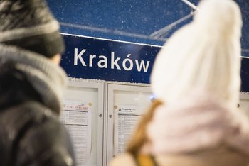 Podróżni stojący przed tablicą z rozkładem jazdy.