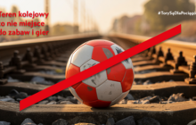 Przekreślona piłka leżąca na torach kolejowych